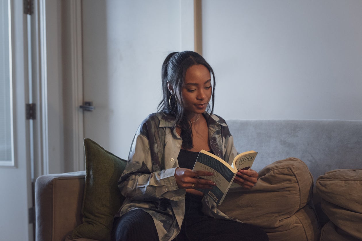 A woman reading on a couch in warm, low light